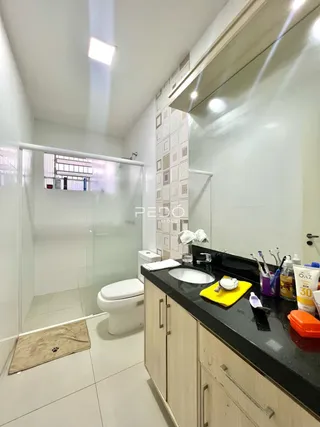 Foto de um banheiro com box de vidro e louças brancas.