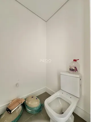 Vista de um canto de banheiro com vaso sanitário e materiais de construção no chão.