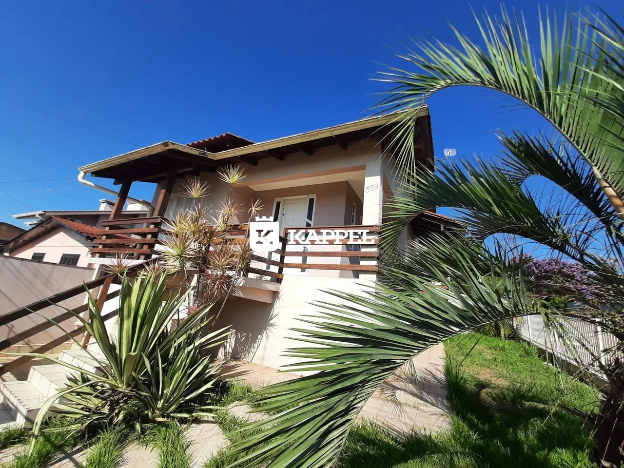 Fachada de uma residência em Lajeado, Brasil, com vegetação tropical em primeiro plano.