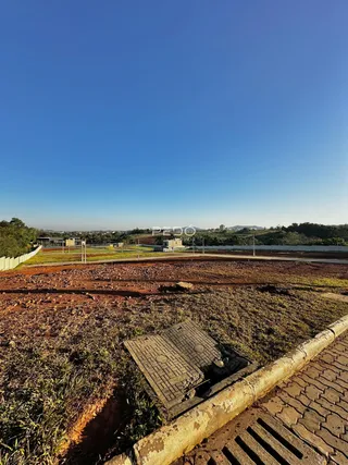 Paisagem de terra e vegetação em uma área aberta com um caminho de concreto.