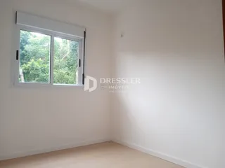 Quarto com janela de grande porte e piso de madeira clara.