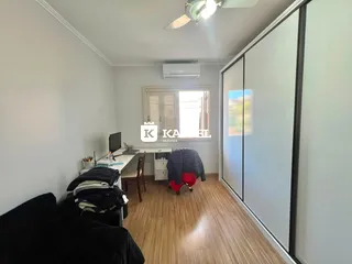 Quarto com cama e escrivaninha em um ambiente claro com piso de madeira.