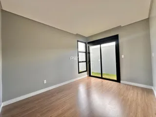 Sala de estar com piso de madeira clara e porta de vidro que dá para o exterior.