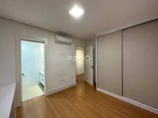 Hall de entrada com piso de madeira e acesso a um banheiro.