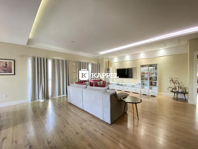 Sala de estar ampla com sofá e televisão em ambiente claro.