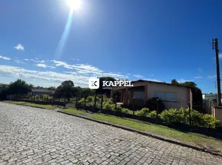 Foto da fachada de uma residência em Lajeado, Brasil, com uma rua de paralelepípedos em primeiro plano.