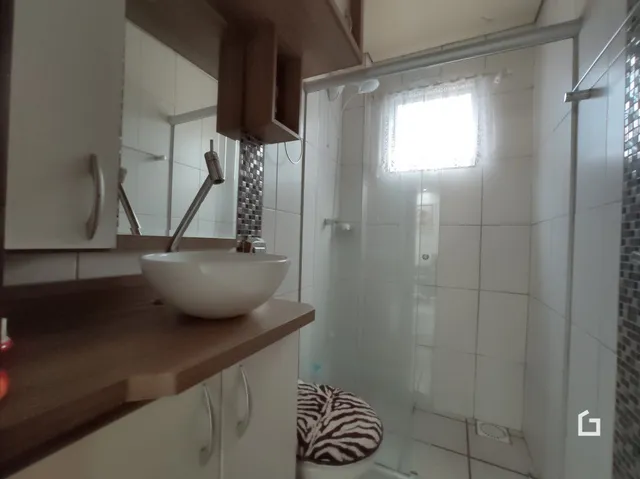 Foto de um banheiro com pia e box de vidro.