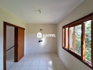 Ambiente interno com piso de cerâmica e grandes janelas que dão vista para a vegetação.