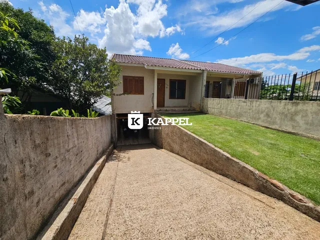 Foto da fachada de uma residência em Lajeado, Brasil, com jardim gramado e muro de contenção.