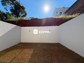 Vista de um terreno com grama seca e muros brancos.