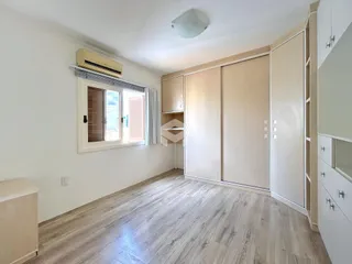 Quarto com piso de madeira e armários embutidos na parede.
