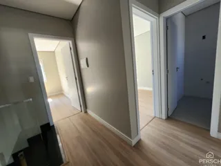 Foto de um corredor interno com piso de madeira e paredes brancas.