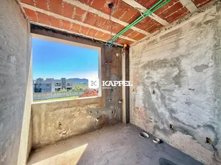 Vista interna de um cômodo com paredes de concreto aparente e teto de tijolos exposto.