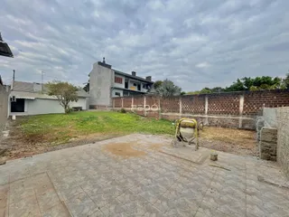 Vista externa de uma propriedade em Lajeado, Brasil, com muro de tijolos e área gramada.