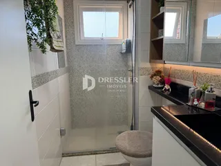 Foto de um banheiro com box de vidro e revestimento cerâmico.