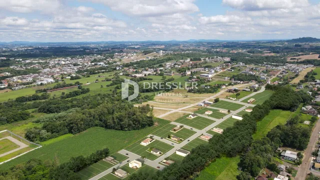 Vista aérea de uma área rural com vegetação e estruturas dispersas.