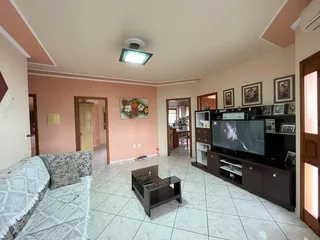 Sala de estar com sofá e rack de televisão em ambiente claro.