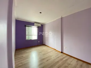 Sala de estar com paredes roxas e piso de madeira clara.
