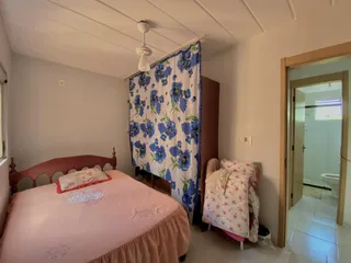 Quarto com cama de madeira e cortina estampada azul e branca.