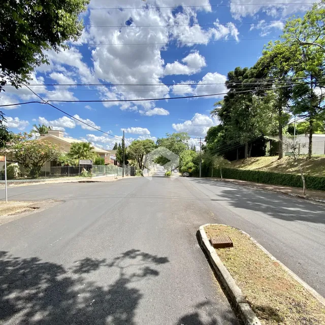 Vista de uma rua residencial em Lajeado, Brasil, com árvores e casas ao fundo.