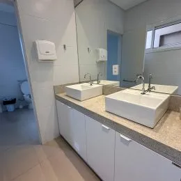Foto de um banheiro com pias brancas e bancada clara.