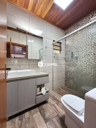 Banheiro com bancada e box de vidro em um imóvel.