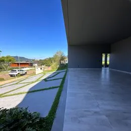 Vista externa de um espaço amplo com piso de concreto e paredes brancas.