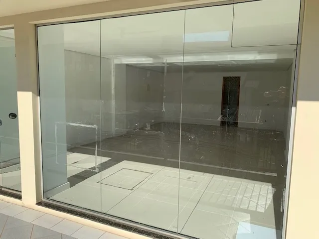 Vista interna de um ambiente com grandes painéis de vidro em uma propriedade em Lajeado.
