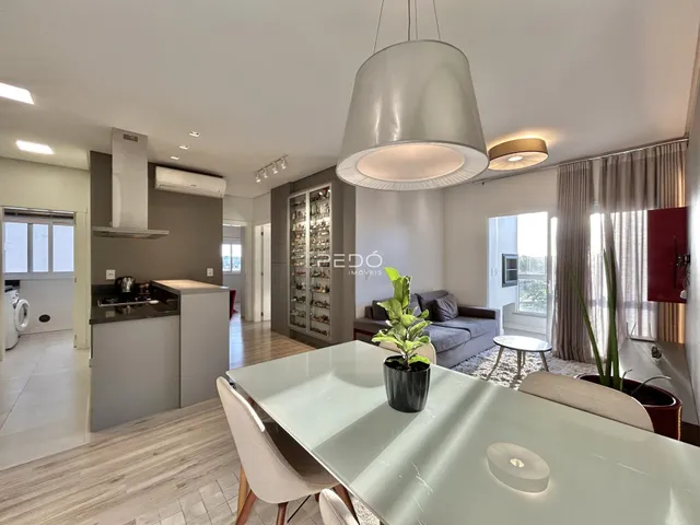 Sala de estar e jantar moderna com piso de madeira clara e iluminação embutida.