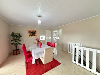 Uma sala de jantar com mesa posta e cadeiras vermelhas é apresentada na propriedade.