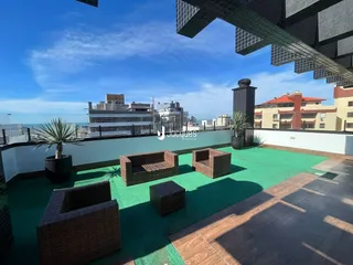 Vista externa de uma área com piso verde e mobiliário de exterior.