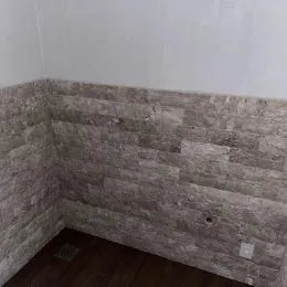Parede com textura de pedra aparente em um ambiente interno.