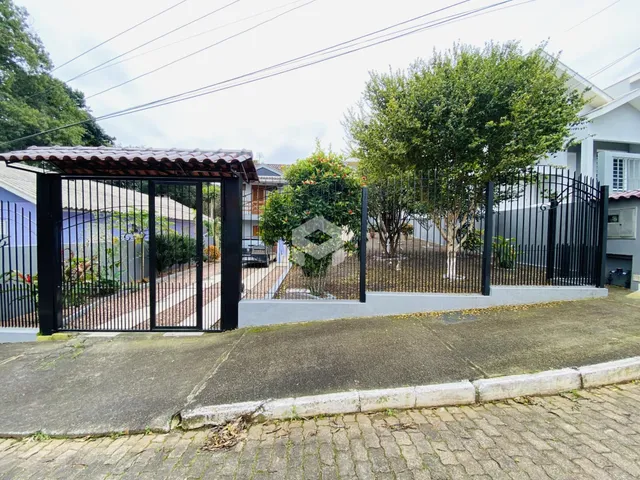 Vista da fachada de uma propriedade com portão de ferro e cerca no Brasil.