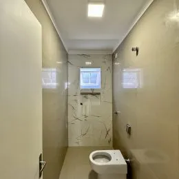 Corredor interno com paredes claras e janela no final.