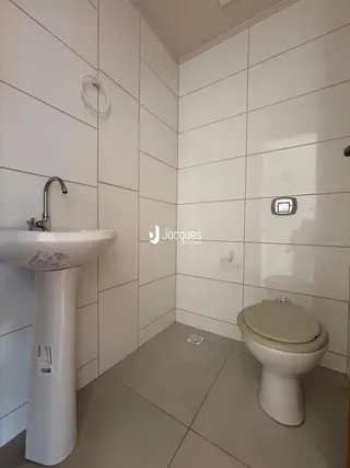 Foto de um banheiro com revestimento cerâmico e louças brancas.