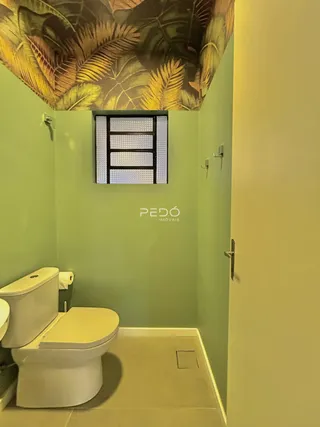 Foto interna de um banheiro com piso claro e decoração de parede verde.