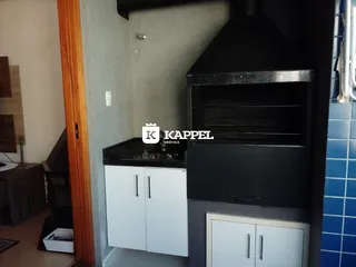 Vista parcial de uma cozinha com armários brancos e exaustor preto.