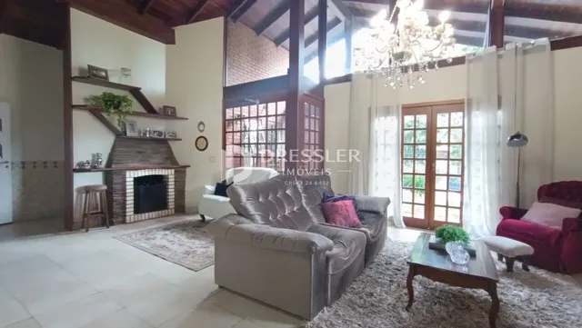 Sala de estar com lareira e grandes janelas em um imóvel no Brasil.