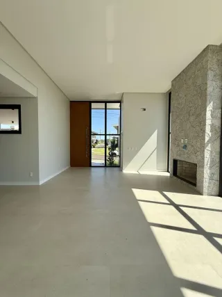 Ambiente interno amplo com piso claro e portas de vidro que dão acesso a outra área.