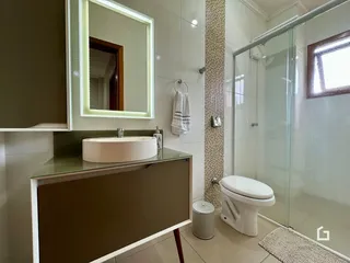 Banheiro com box de vidro e piso claro.