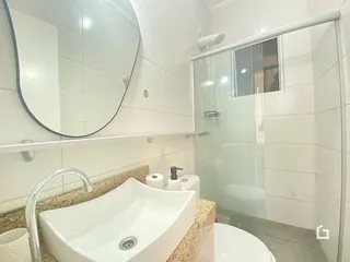 Banheiro com box de vidro e pia de granito.