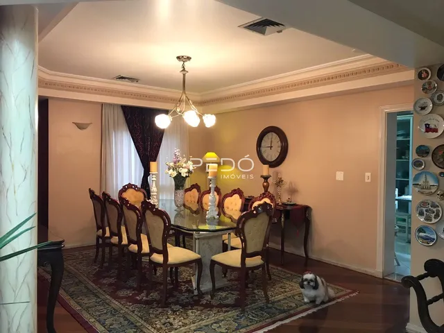 Ambiente interno de uma sala de jantar com mesa e cadeiras decorativas.