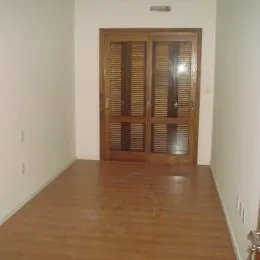 Foto de um corredor com piso de madeira clara.