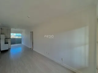 Corredor interno de uma residência com piso de madeira clara e paredes brancas.