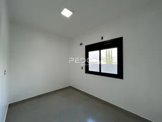 Ambiente interno de uma sala vazia com paredes brancas e piso cinza claro.