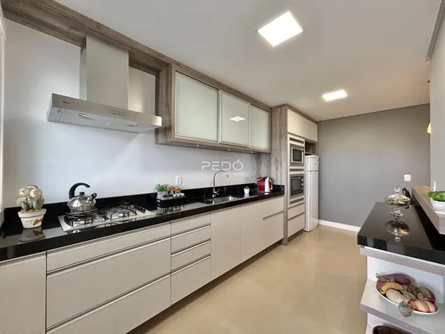 Cozinha moderna com armários brancos e bancadas escuras.