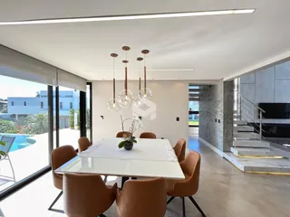 Vista de uma sala de jantar moderna com mesa de vidro e cadeiras.
