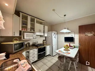 Cozinha com armários brancos e piso cerâmico em imóvel no Brasil.