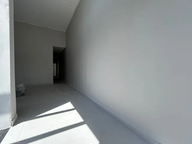 Hall de entrada com piso de concreto e paredes brancas.