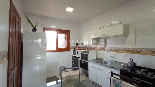 Vista da cozinha com armários brancos e piso de cerâmica.